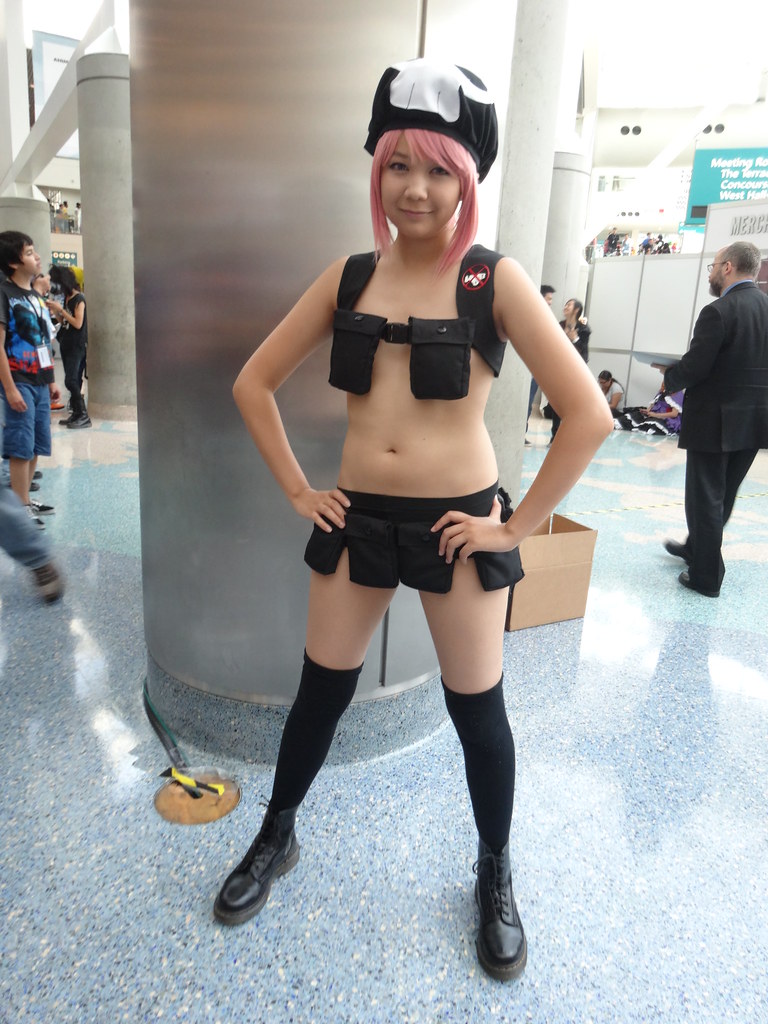 Image of a woman in a risqué cosplay outfit that consists of military style belts with lots of pockets but no actual clothes (Nudist Beach Nonon).