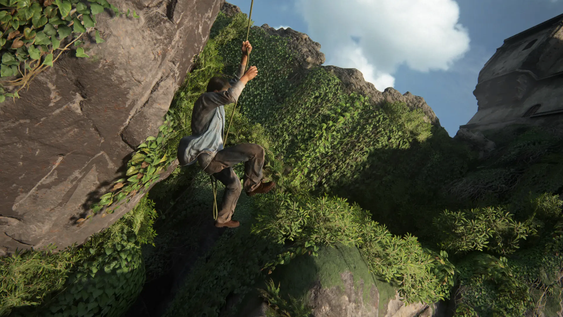 A man climbs a rope between steep cliffs covered in lush green vegetation, with a tall stone structure visible at the top right.