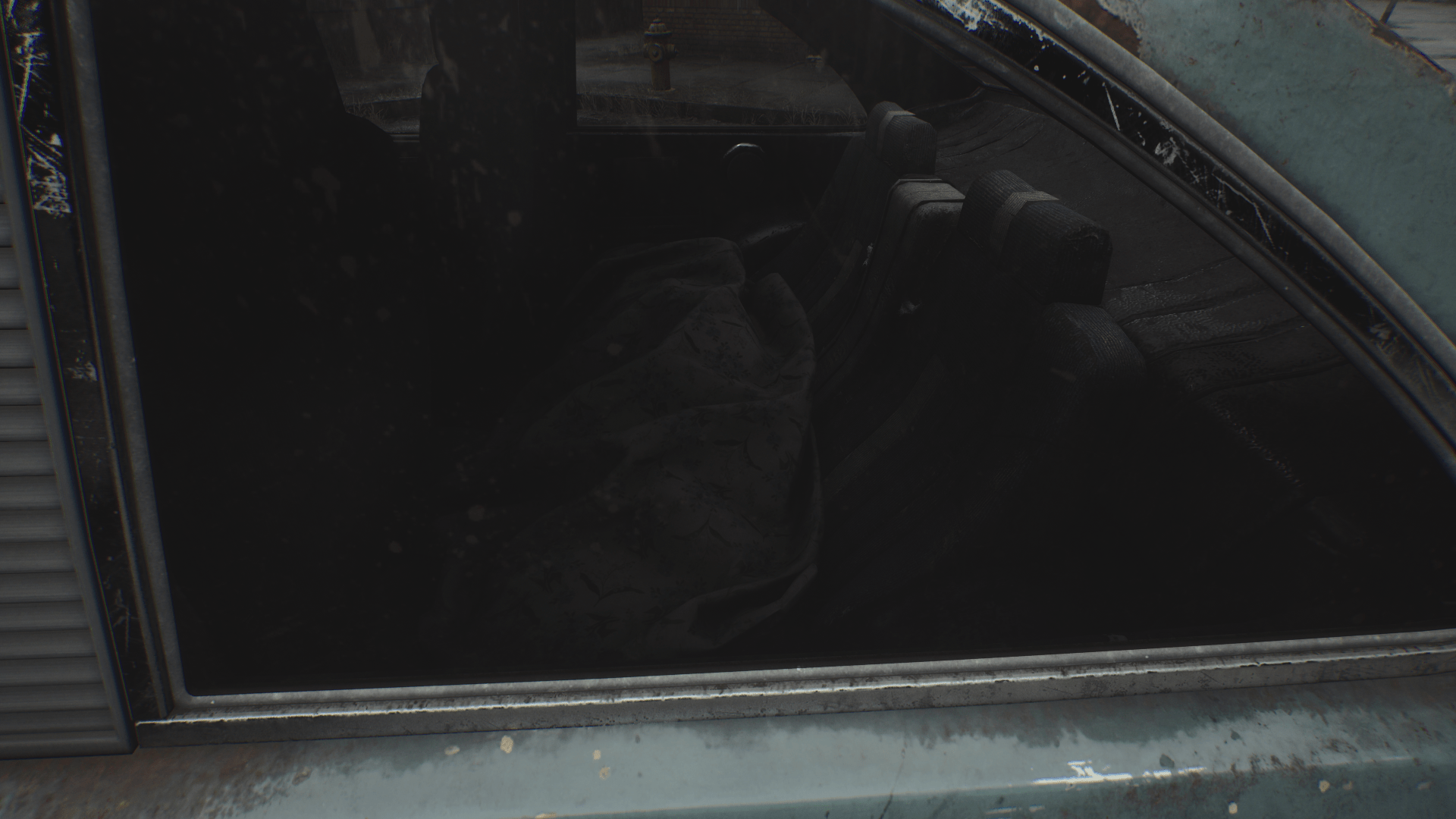 A dark, abandoned car interior viewed through a dusty window, with a shadowy, indistinct object on the back seat.