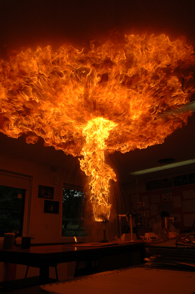 A pillar of fire erupts from a stand and spreads out onto the ceiling